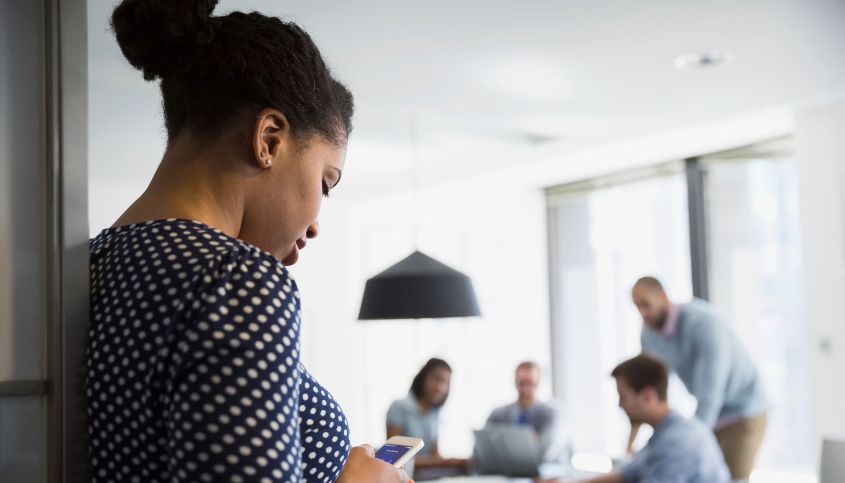 Businesswoman texting cell phone outside conference room meeting