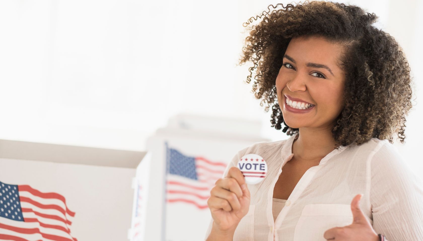 Young woman holding voting badge and smiling
