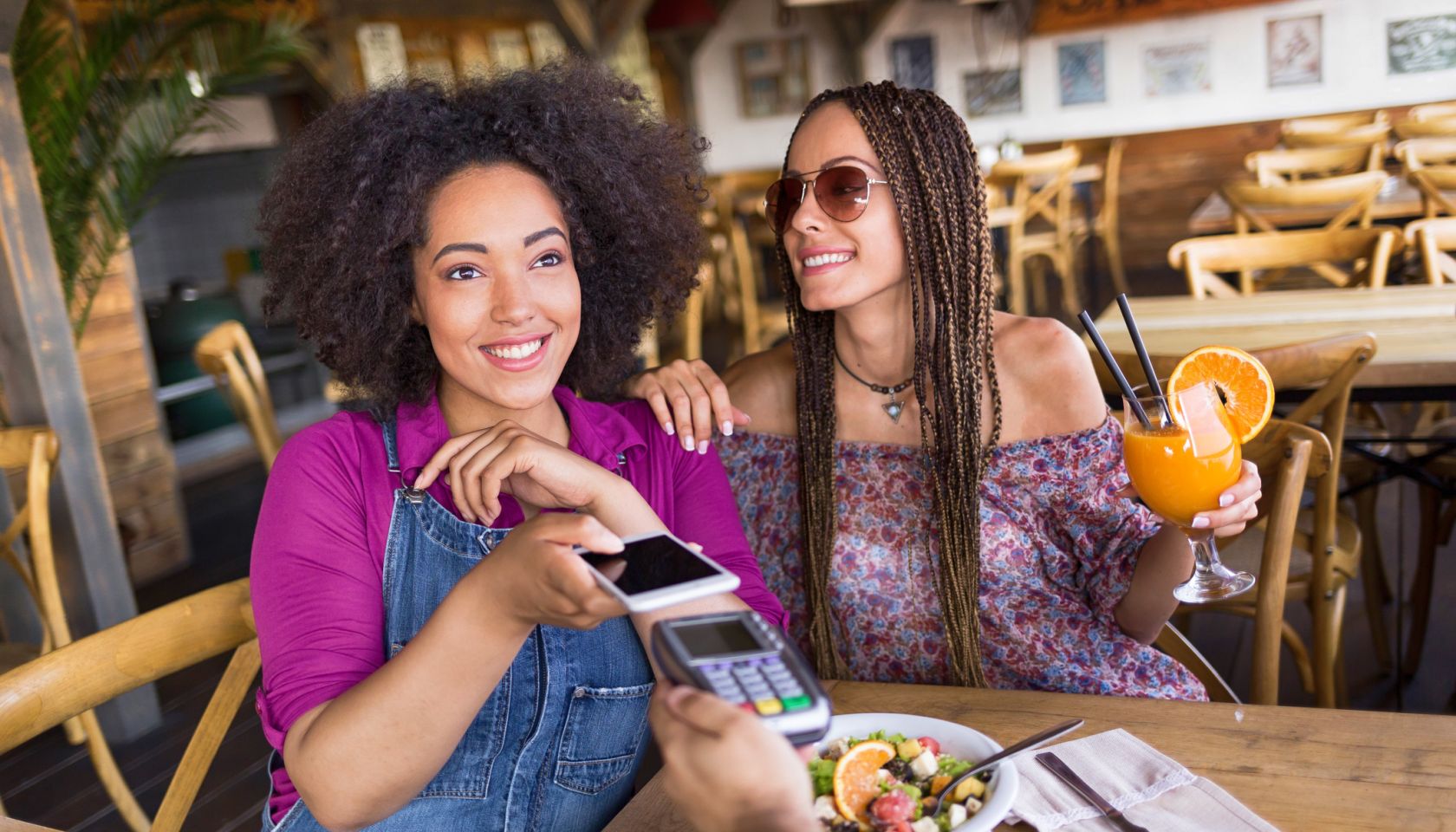 Cheerful frineds using smart phone for mobile payment