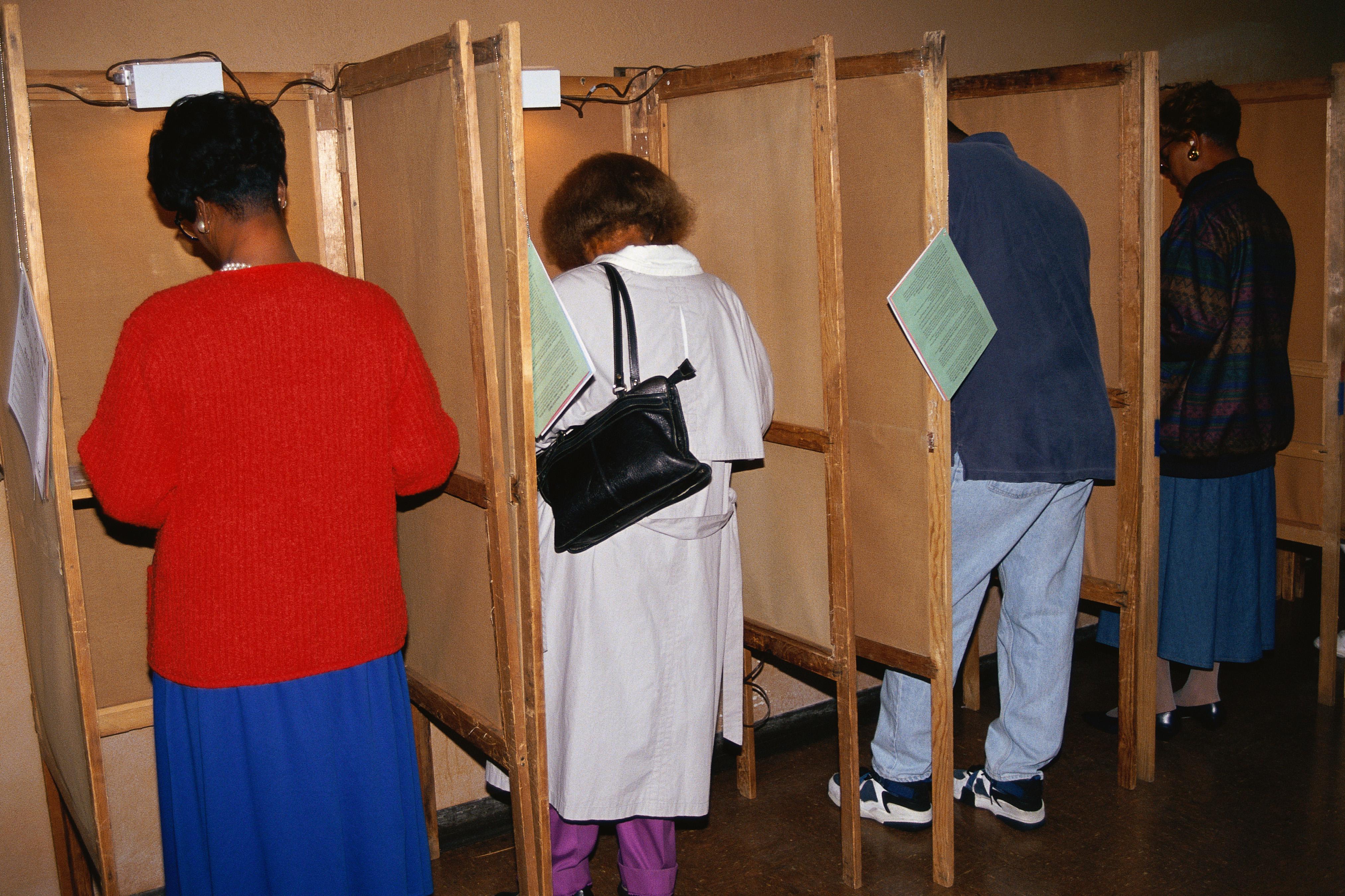 Voters selecting candidates in voting booths
