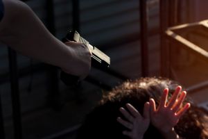 Cropped Hand Of Criminal Aiming Gun Towards Woman At Home