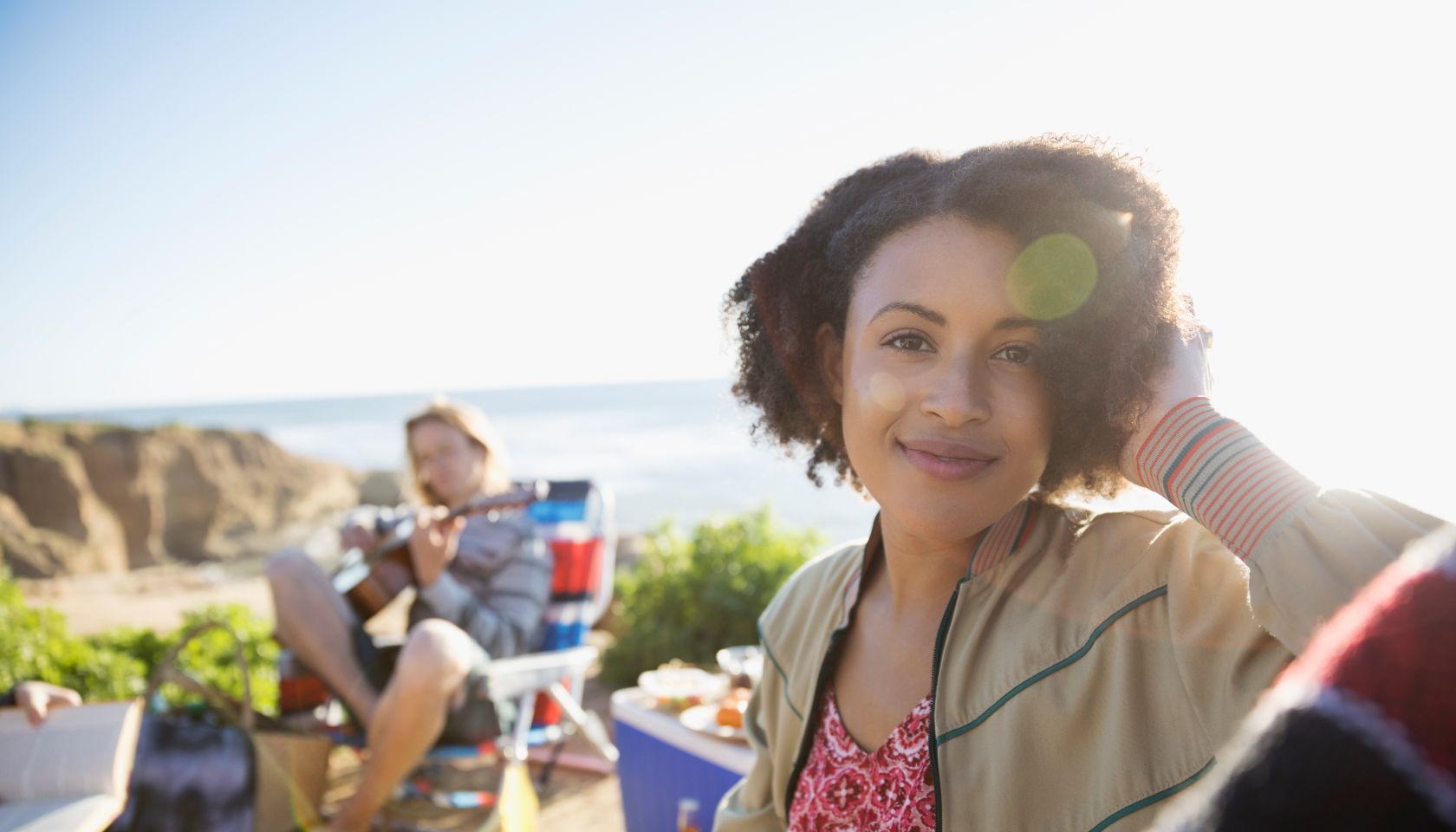 Portrait smiling young woman enjoying picnic with friends on sunny beach