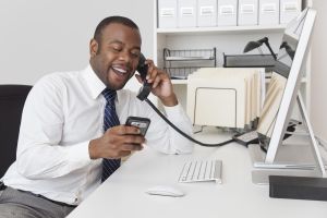 Black businessman using two telephones at one time