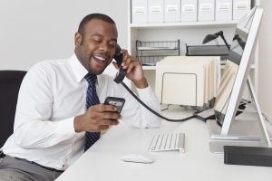 Black businessman using two telephones at one time