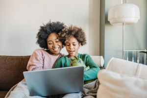 Young mother is using laptop at home with hers daughter