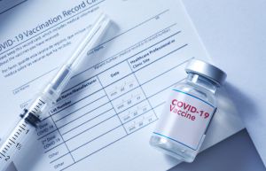 Covid-19 vaccination record card with a vial of a Covid-19 booster dose