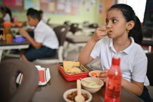 School girl eating healthy lunch during lunch break in classroom