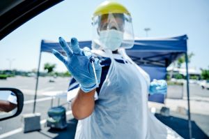 Shot of a masked nurse wearing a face shield while holding a cotton-tipped swab outside