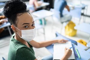 Portrait of a teenage student in the classroom - using a face mask