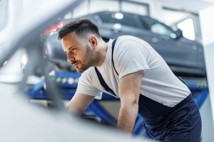 Auto mechanic examining engine problems in a workshop.