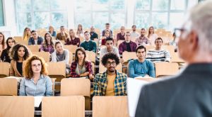 Large group of college students listening to their professor on a class.