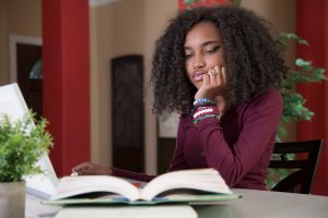 African American teenage girl stressed over e-Learning and homework.
