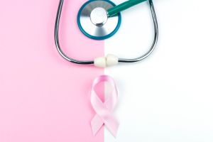 Pink ribbon and stethoscope against pastel colored ackground.