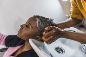 Hairdresser washing a black woman's head in the sink
