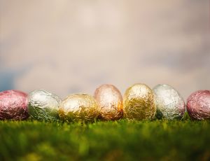 Easter background with foil wrapped Easter eggs in grass with sky background