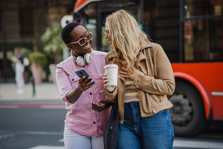 Two female friends walking on the street an smiling