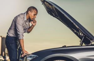 African American man calling for help after vehicle breakdown on the street.