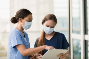 Female surgeons wear masks to prevent illness while discussing chart