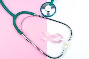 Pink ribbon and stethoscope against pastel colored ackground.