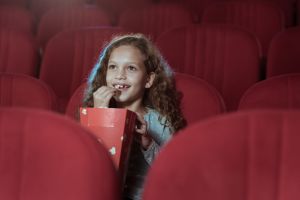 Girl in cinema watching movie and eating popcorn