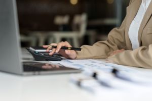 Midsection Of Woman Using Calculator At Table