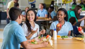 Diverse teenage friends eat lunch in school cafeteria