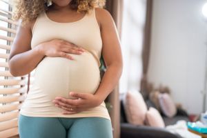 Portrait of young pregnant woman standing by the window