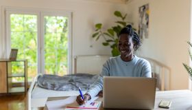Modern female student Black ethnicity using laptop, while studying from her college dorm