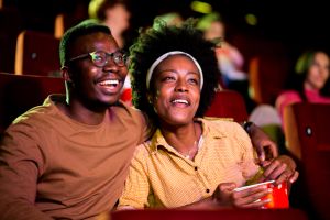 African-American couple laughing while watching a fun movie at the cinema