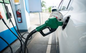 Transport and industry concept. Refilling the car. A refueling valve is inserted into the fuel filler neck. White car at gas station being filled with fuel