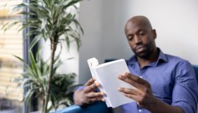 Black man reading a book at home