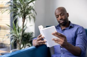 Black man reading a book at home