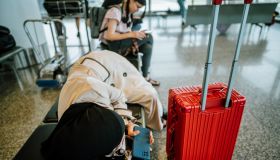 Young Asian business woman with hijab waiting for delayed flight and sleeping on chairs at airport