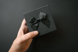 Black gift box in female hand over black background, Black Friday concept