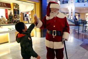 Santa Claus high fives with a youngster while greeting holiday shoppers at the Stonestown Galleria shopping mall San Francisco, Calif. on Wednesday, Nov. 21, 2018. Daniel Halkyard has been portraying Santa for 45 years but this is first time at Stonestown
