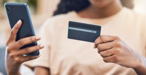Black woman with a phone uses credit card for digital, online shopping and to buy ecommerce goods. Web security technology makes paying bills using fintech easy, simple and safe for retail customers
