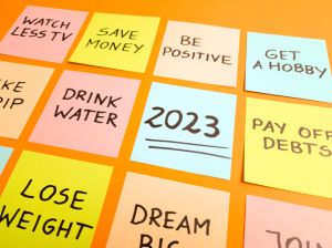 New Year 2023 resolutions handwritten on colorful sticky notes on orange background. Future planning, motivation, change and challenge concept