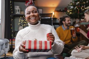 African-American young woman holding a a Christmas present in the living room