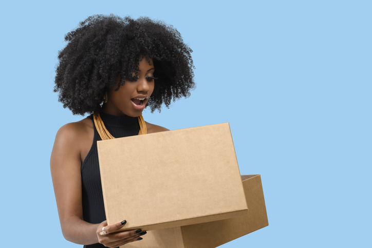 beautiful afro woman opens a box and is positively surprised