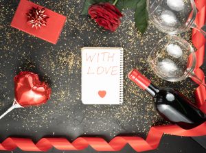 Flat lay background of valentine's day with wine, heart, glasses and gift on black concrete background
