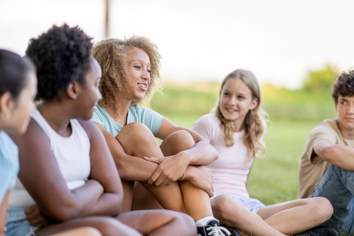Kids sit next to each other on the grass