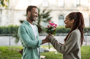 romantic man gives bouquet of flowers to his girlfriend in the street - she is surprised and happy -