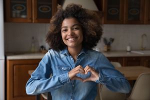 Happy excited teenage Black girl making hand heart shape