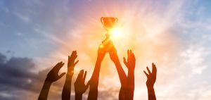 Silhouette Business team holding award trophy show victory business success sunset background. Winning team with trophy cup against shining sun in sky. Man holding trophy cup