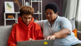 African American mature woman and teenage boy looking at laptop screen