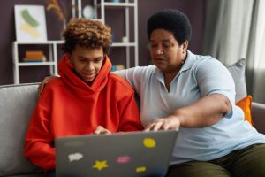 African American mature woman and teenage boy looking at laptop screen