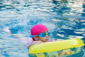 Little girl practicing swimming in the pool. Happy children swimming and playing in the water. summer vacation concept.