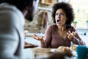 Angry African American couple arguing during breakfast at home.