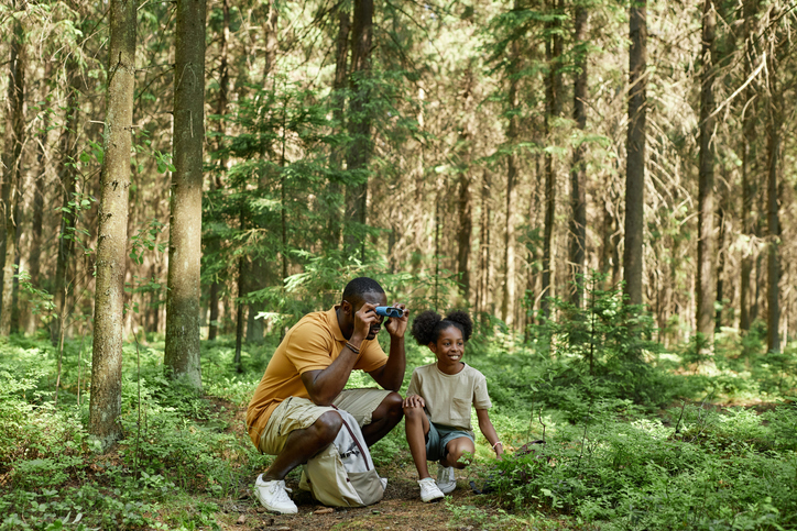 Dad using binoculars with child during hiking