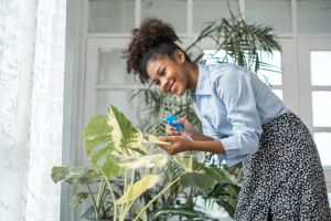 Young women watering the plants in his living room